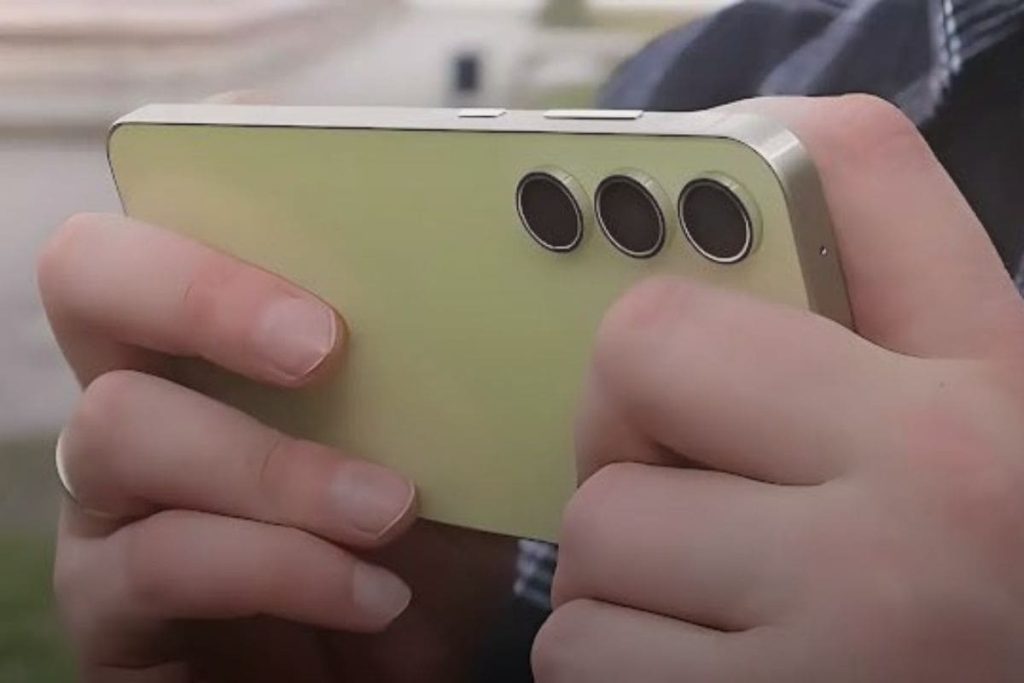 Um homem segurando um Samsung Galaxy A55 deitado